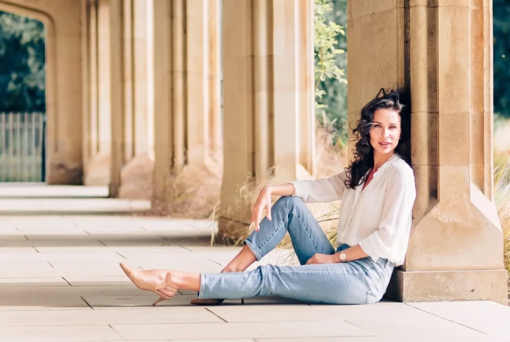 Relaxed portrait of a woman sitting between stone columns at Magdalen College, Oxford