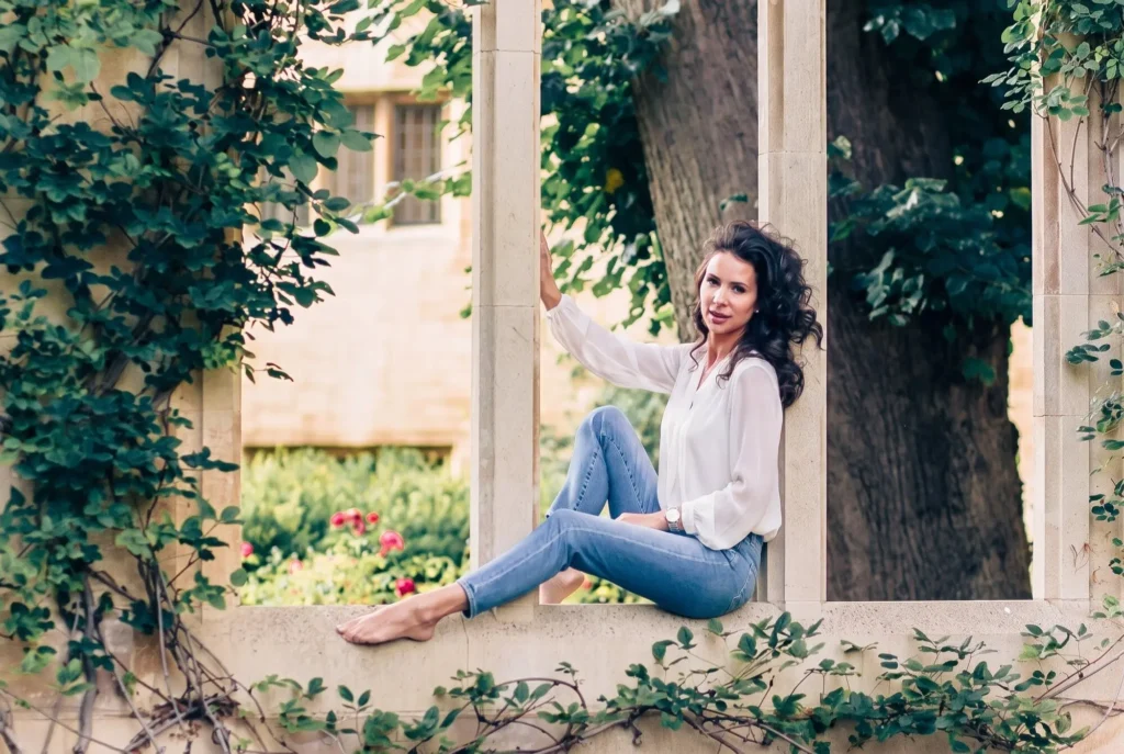 Woman sitting in an ivy-framed stone window at Magdalen College during an Oxford portrait session