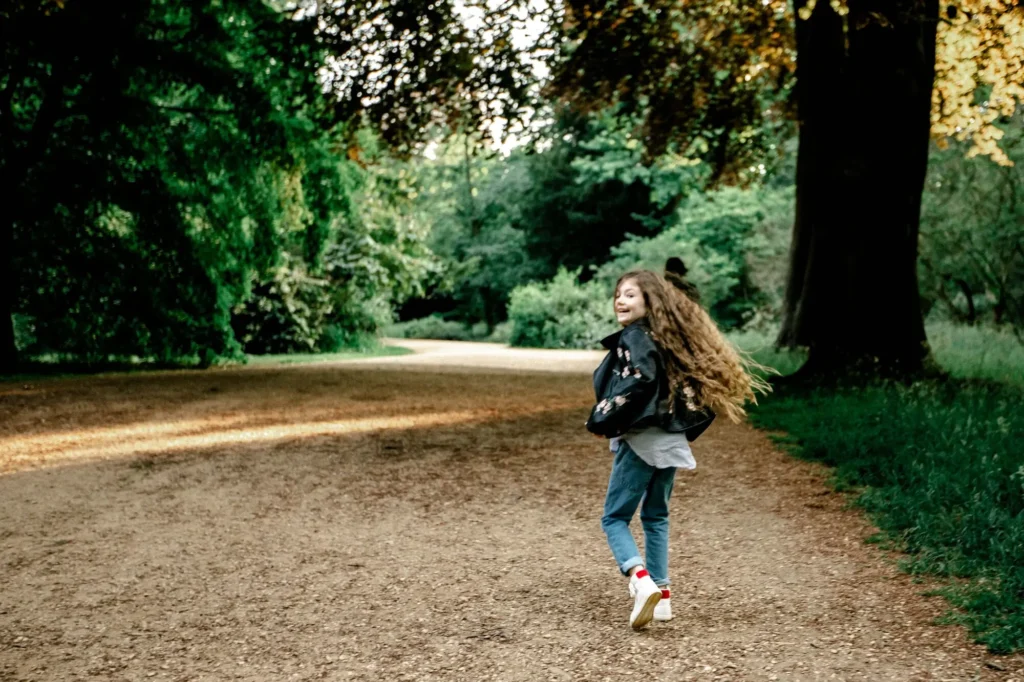 Girl mid-twirl on a park path with hair flying, Oxford children photographer at University Parks