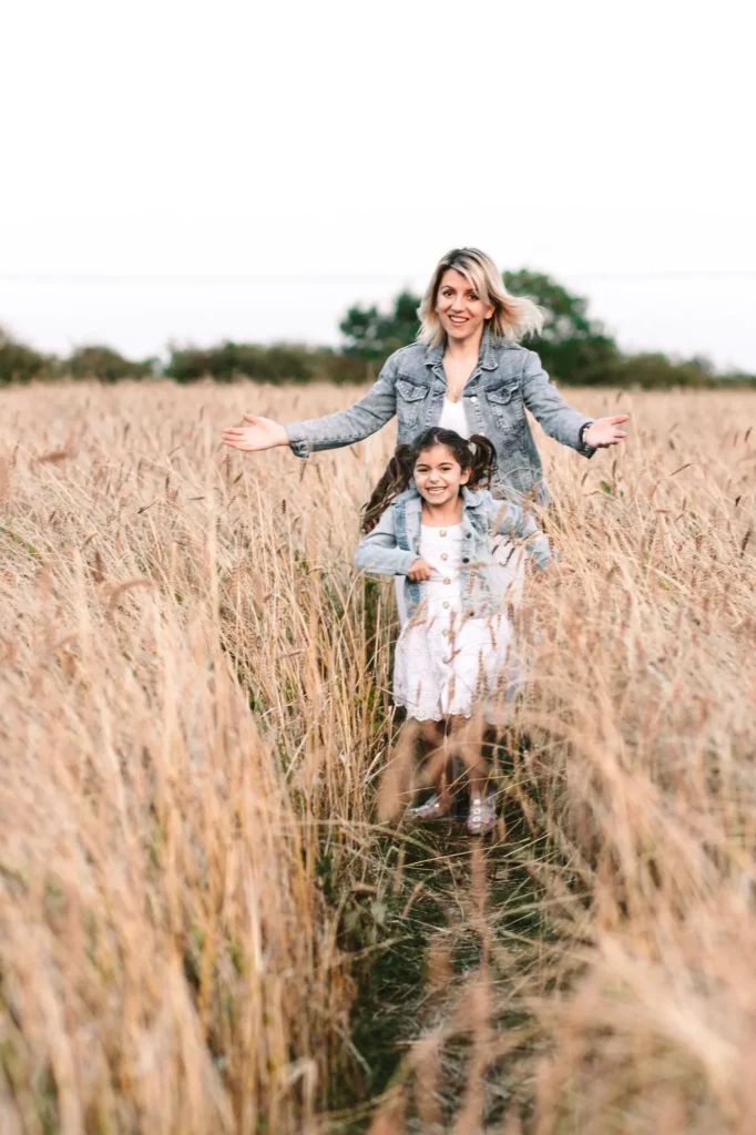 Mother and daughter running together along a wheat field path, candid Oxfordshire family photography