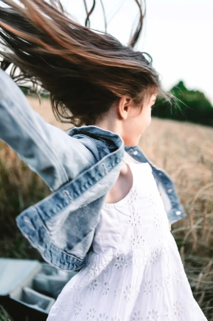 Young girl's hair blowing in the wind in a sunlit field, candid Oxfordshire children photography