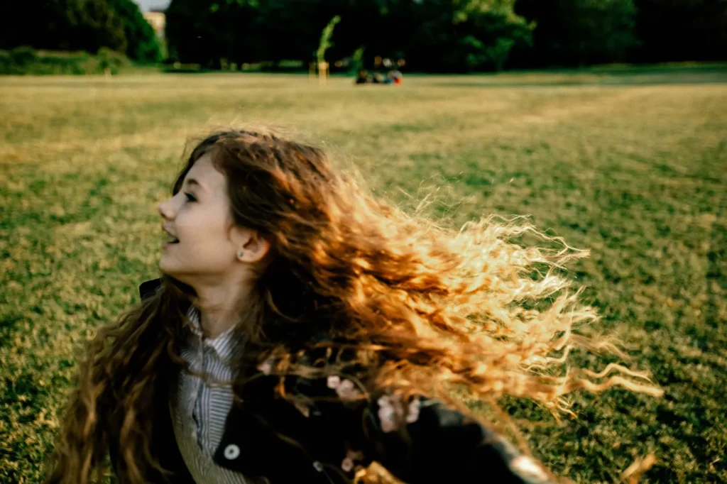 Girl with windswept hair lit by golden sunlight in University Parks, Oxford children photography