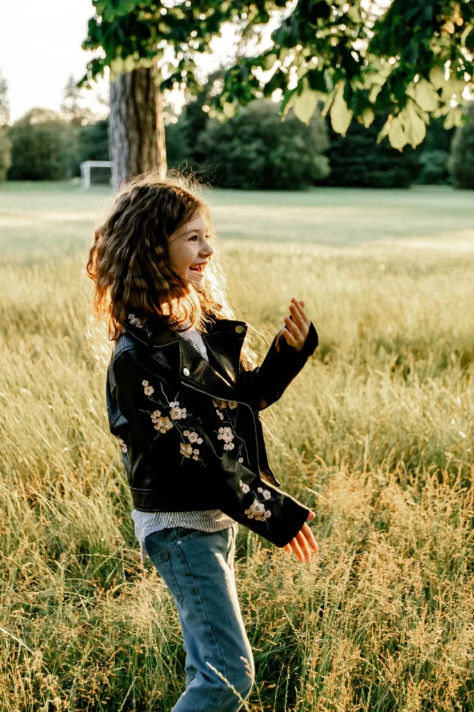 Girl laughing in profile standing in tall golden grass, Oxford children photography at University Parks