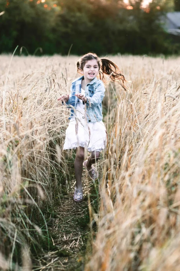 Little girl in a denim jacket running through a wheat field, Oxfordshire children photography