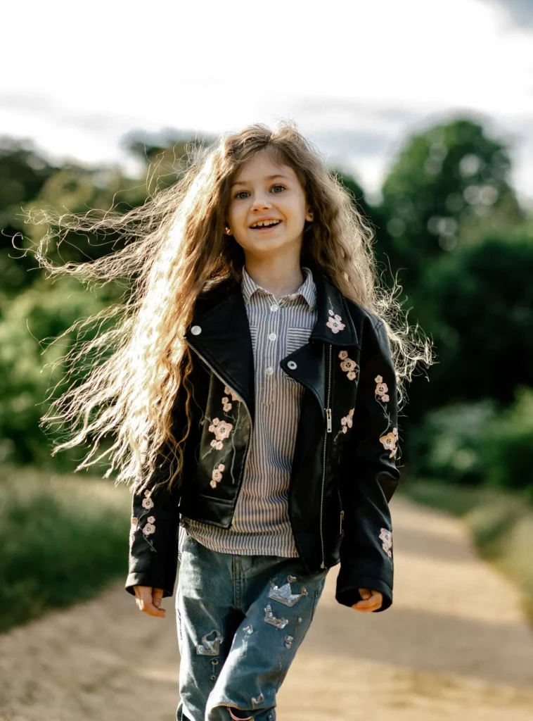 Girl walking toward the camera with hair blowing sideways, Oxford children photography at University Parks