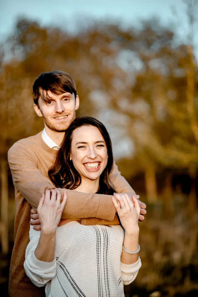 Engaged couple smiling together outdoors, photographed by an Oxford portrait photographer