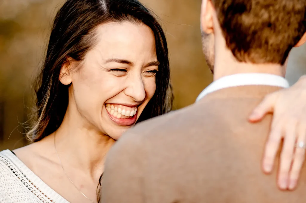 Close-up of a woman laughing on her partner's shoulder, intimate Oxford engagement photography