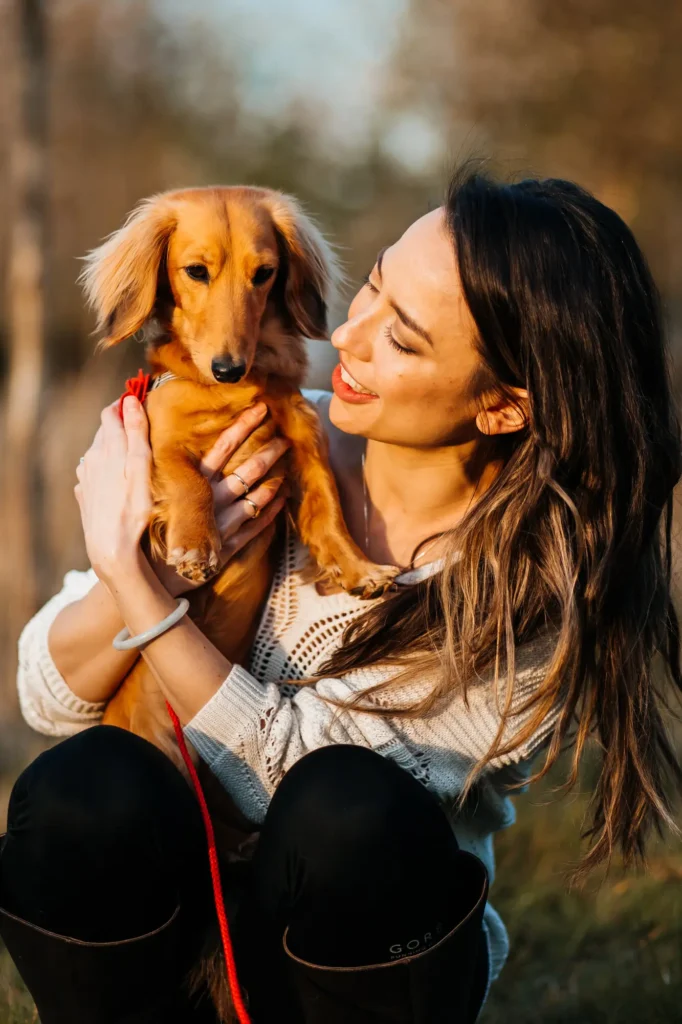 Woman smiling at her dachshund puppy during an outdoor Oxfordshire engagement photoshoot