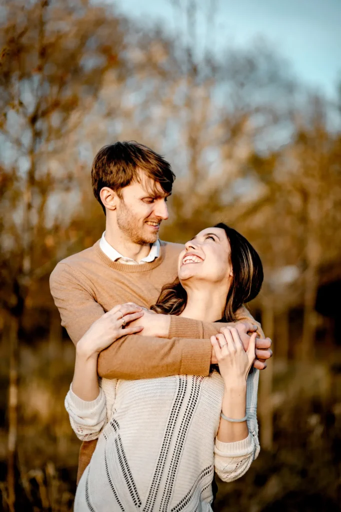 Couple embracing and smiling at the camera in golden hour light, Oxford engagement portrait