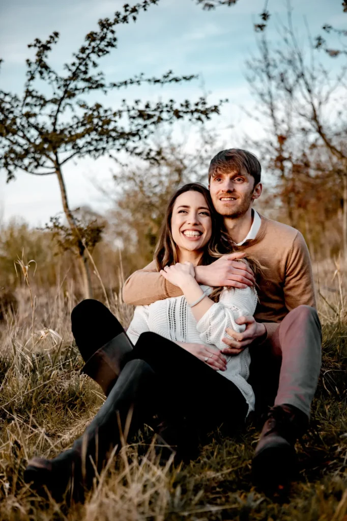 Engaged couple sitting together in a golden autumn field, Oxfordshire portrait photography