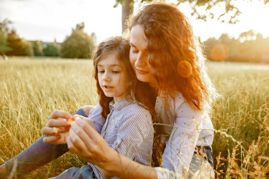 Mother and daughter looking closely at something held in hand, golden hour light at University Parks