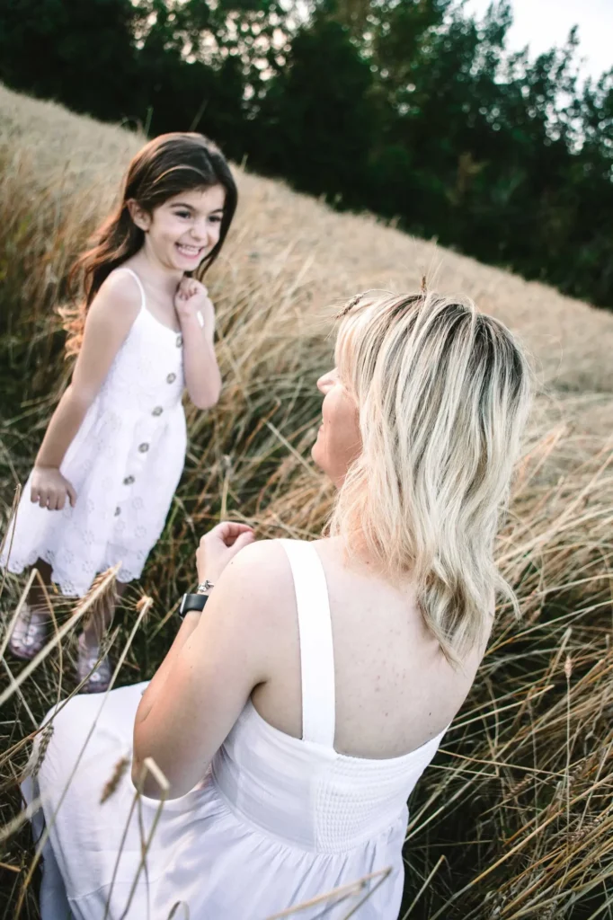 Daughter laughing as her mother turns to look at her in a wheat field, Oxford family photography