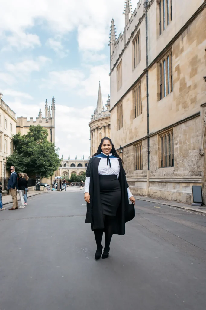 Graduate walking down Catte Street with the Radcliffe Camera dome in the distance